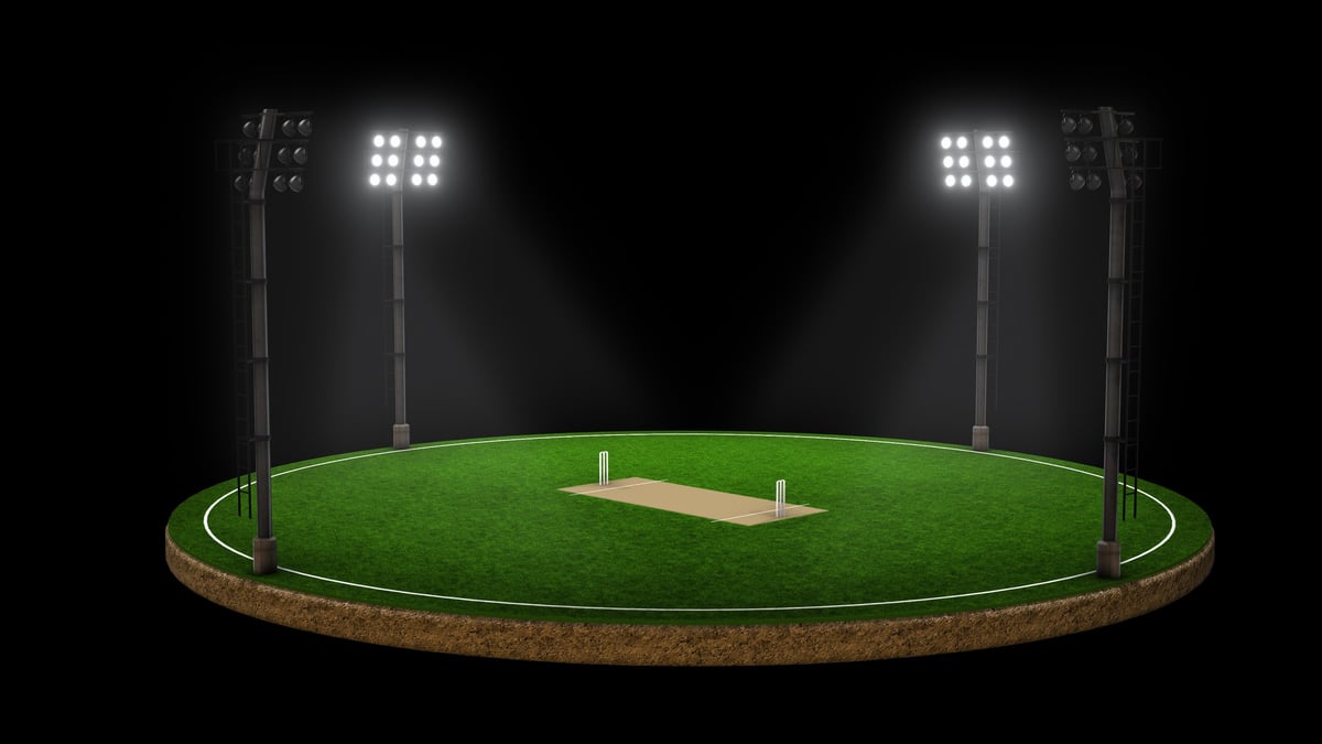 Cricket field illuminated under tall stadium floodlights at night